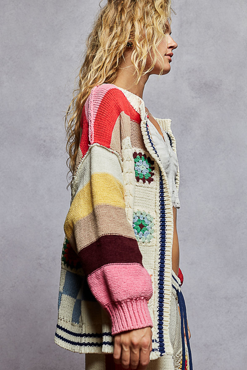 Woman wearing a colorful, patterned cardigan against a gray background