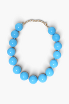 A light blue beaded necklace with large glossy round beads and a gold-tone chain extender clasp, displayed on a clean white background.