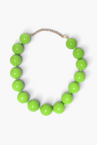 A chunky beaded necklace made of glossy, bright lime green spherical beads, connected by a delicate gold-tone chain extender, shown on a clean white background.