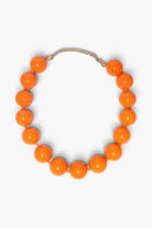 A chunky beaded necklace made of glossy, bright orange spherical beads, connected by a thin silver-toned chain extender, shown on a clean white background.