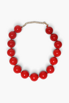 A red beaded necklace with large glossy round beads and a gold-tone chain clasp, photographed on a clean white background.