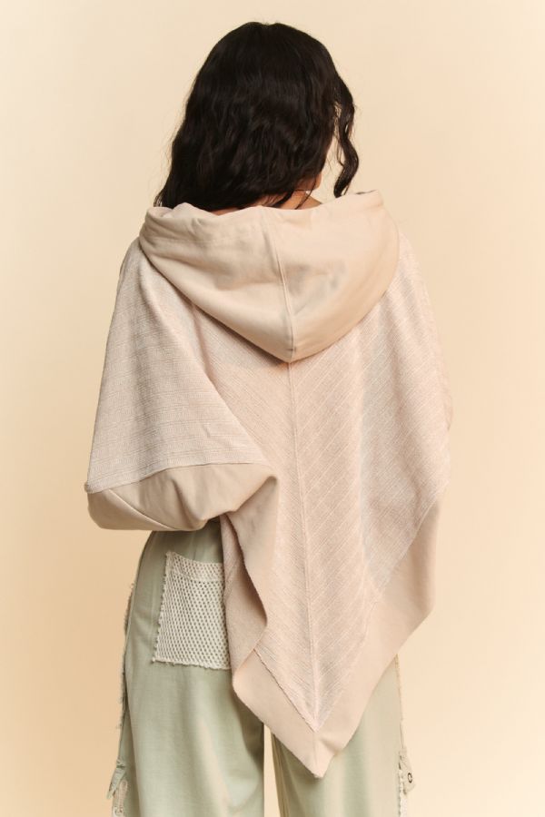 Person wearing a light-colored shawl over shoulders against a beige background