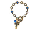 Bracelet with gold chain, blue gemstones, and a cross charm on a white background