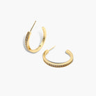 A pair of gold-colored hoop earrings with pave (small stones) on the hoop surface.