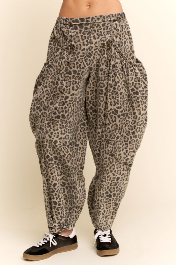 Leopard print pants worn by a person on a beige background