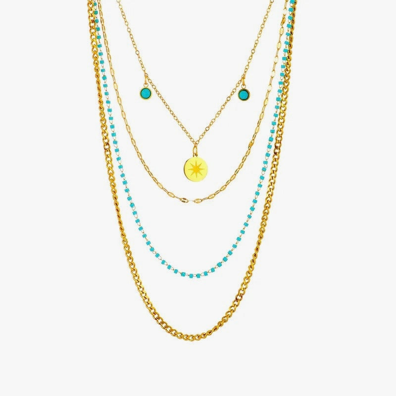 A set of layered gold-colored necklaces with turquoise accents and a central gold pendant.