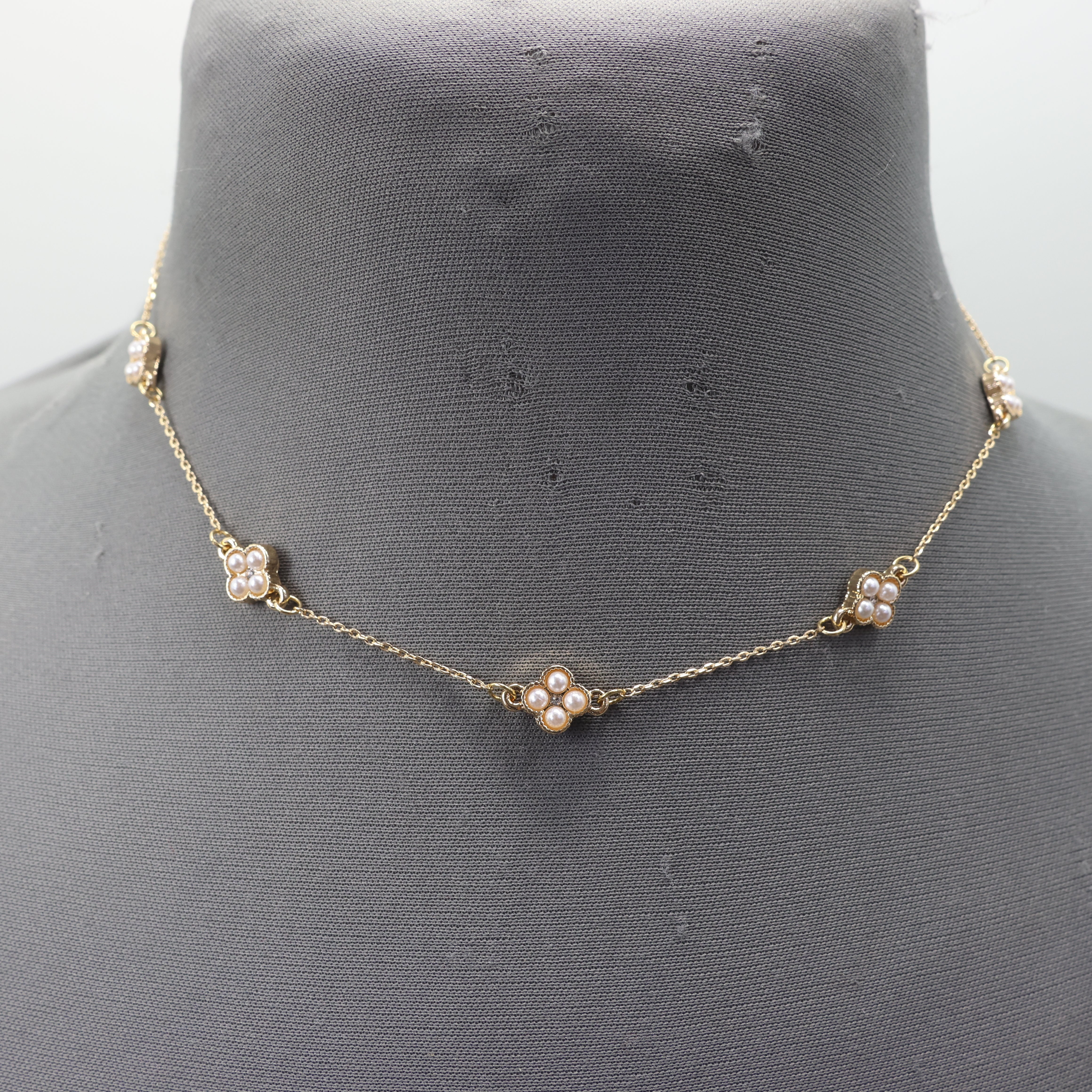 Gold necklace with pearl-like beads on a mannequin bust.