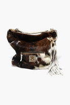 Brown and white cowhide handbag with tassel on a white background