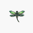 Green dragonfly-shaped brooch with gemstones on a white background