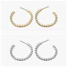 A pair of gold-colored hoop earrings with open hoops and sparkling stones, displayed against a white background.