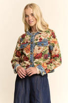 Woman wearing a floral jacket with denim accents on a beige background