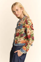 Woman wearing a floral denim jacket on a beige background