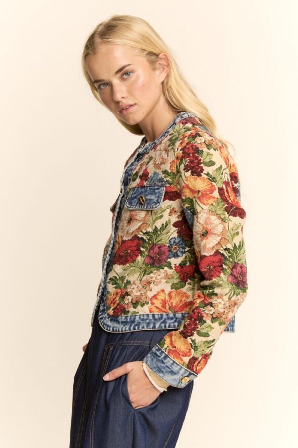 Woman wearing a floral denim jacket on a beige background