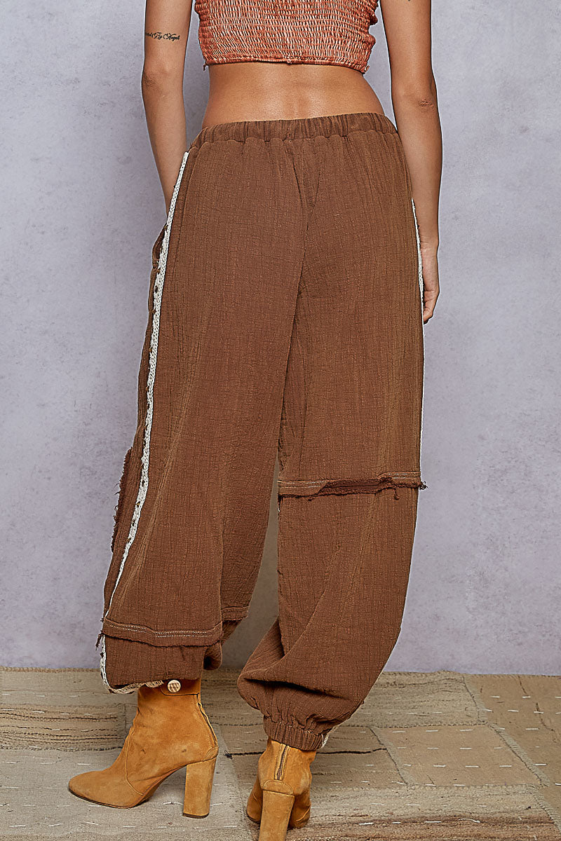 Brown pants with white stripes worn by a person on a neutral background