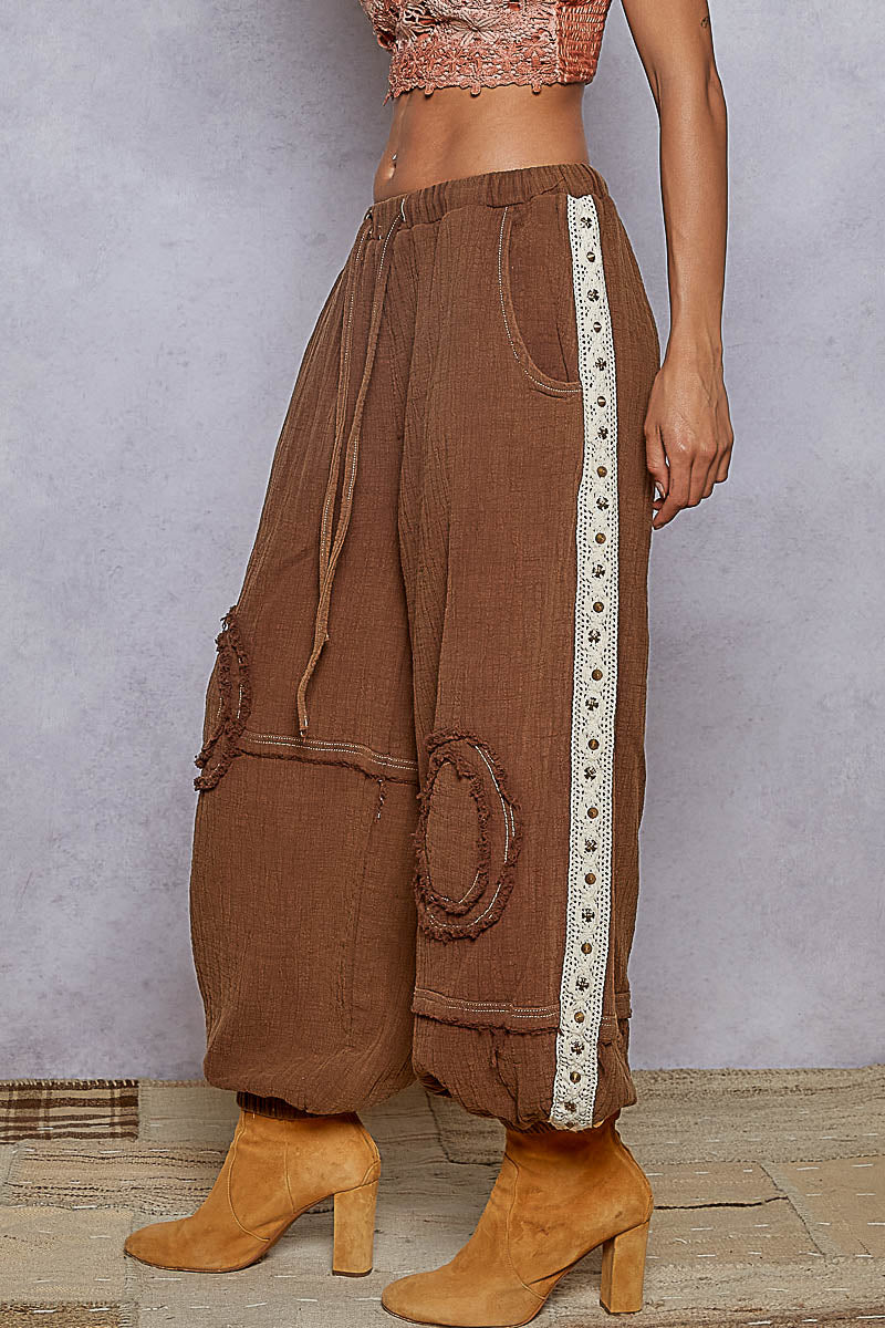 Brown wide-leg pants with a white stripe on a neutral background
