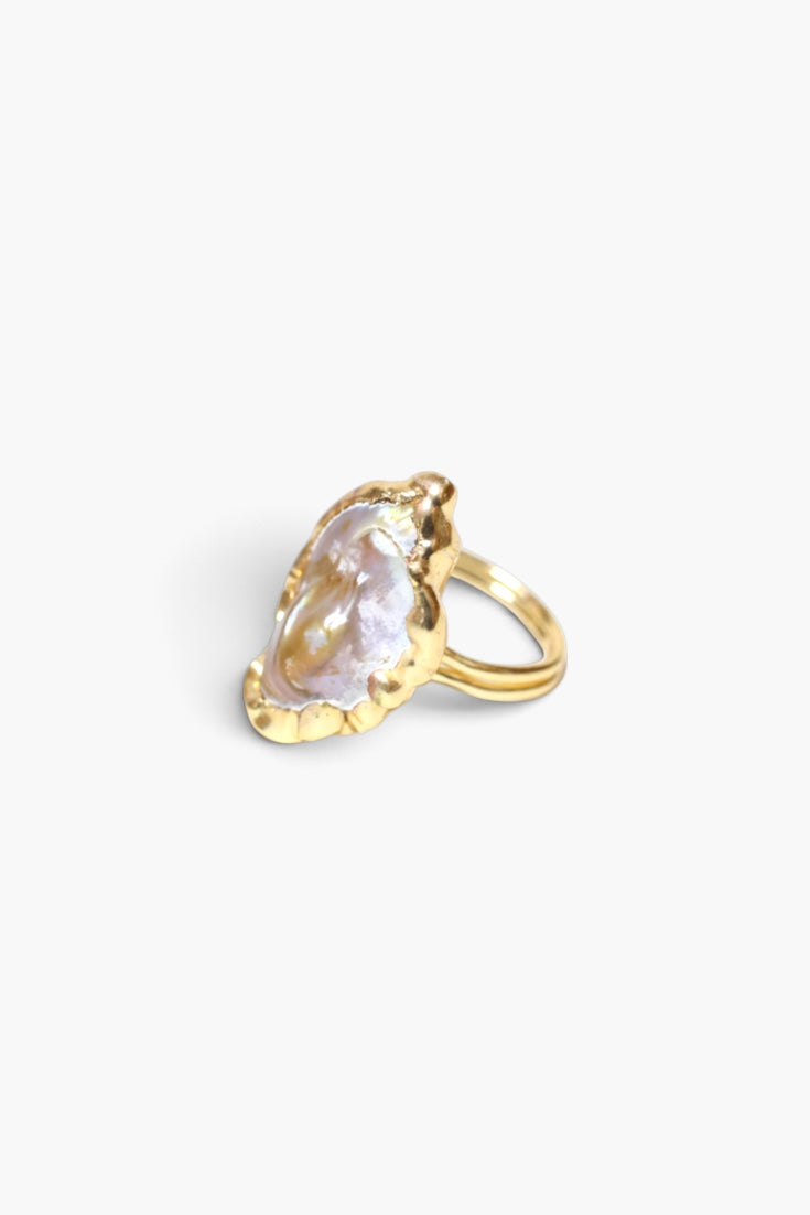 A gold ring featuring a large, irregularly shaped pear-cut clear gemstone in a textured bezel setting, shown on a plain white background.
