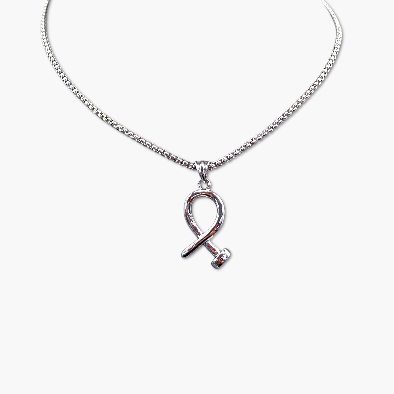 A gold-colored nail necklace with a bohemian and vintage style, featuring a ribbon-shaped charm on a chain.