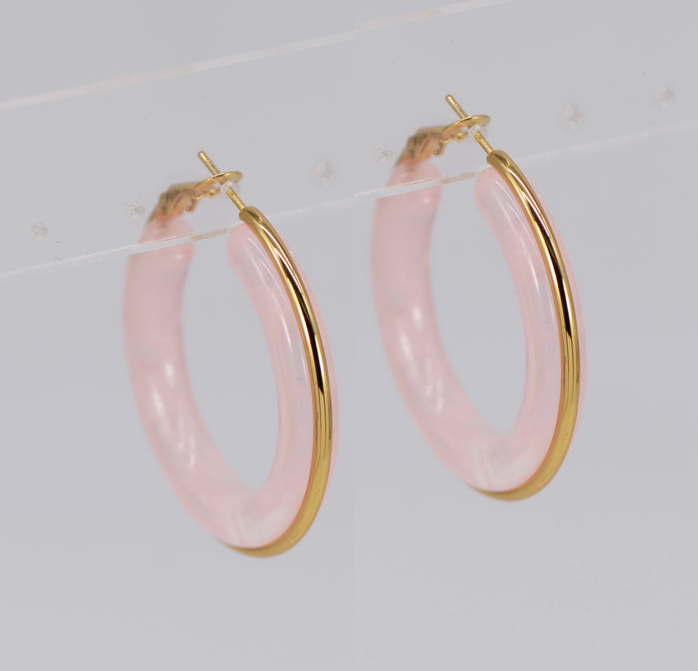 A pair of gold wrapped acrylic hoop earrings with a green marbled pattern.