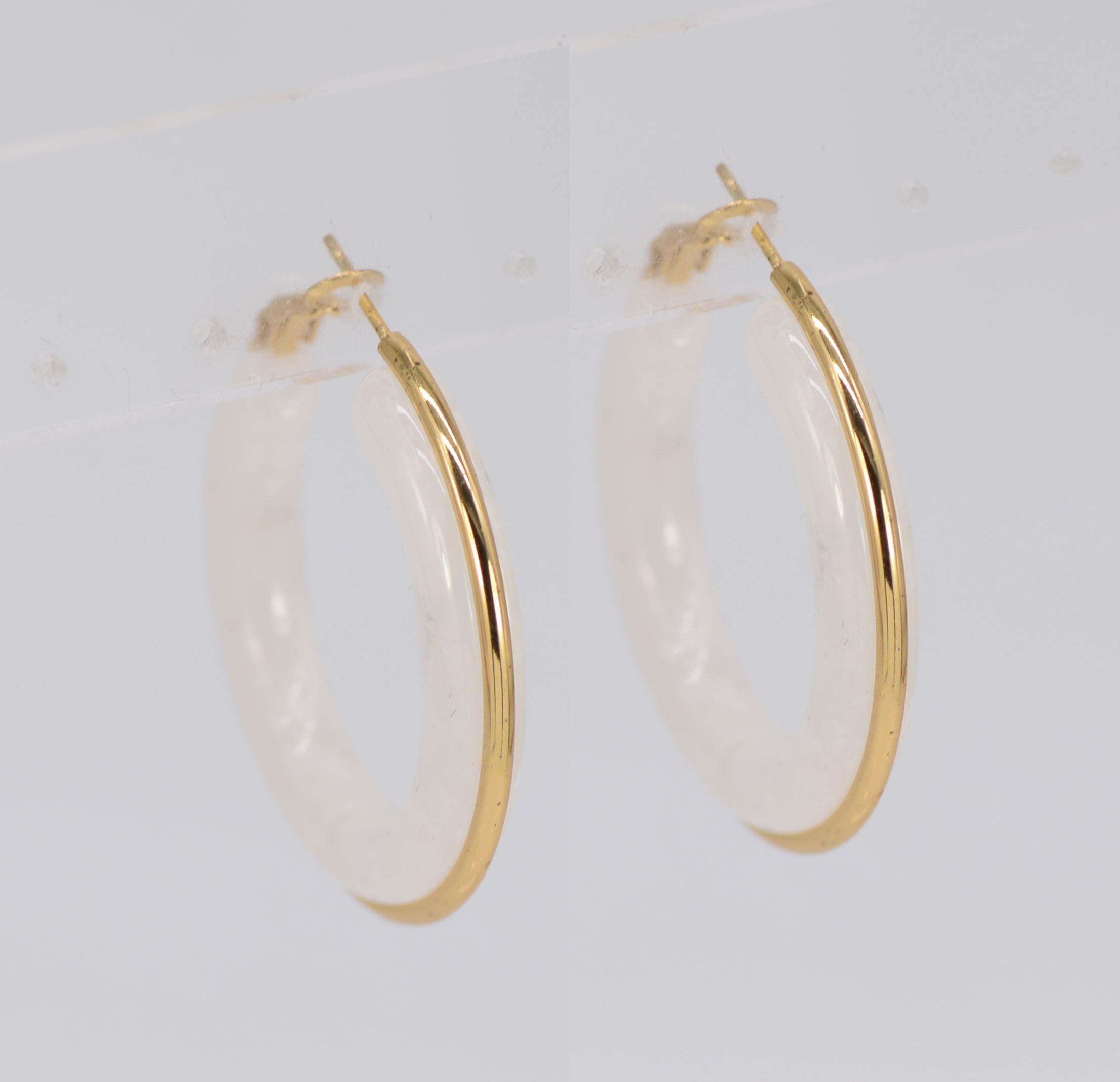 A pair of gold wrapped acrylic hoop earrings with a green marbled pattern.
