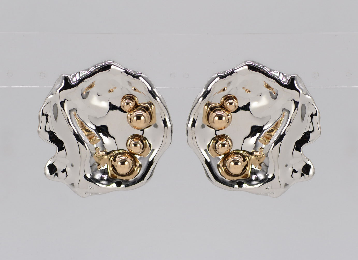 A pair of gold-colored hammered metal earrings with beaded details.