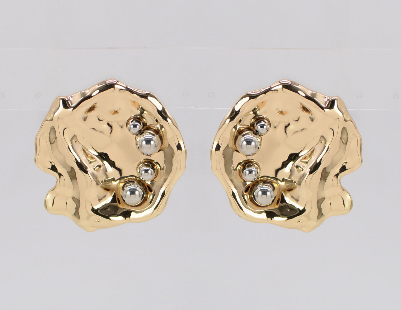 A pair of gold-colored hammered metal earrings with beaded details.