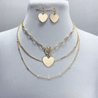 Gold heart-shaped necklace and earrings on a mannequin bust.