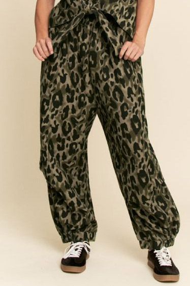 Leopard print pants worn by a person on a beige background