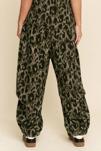 Leopard print pants worn by a person on a beige background