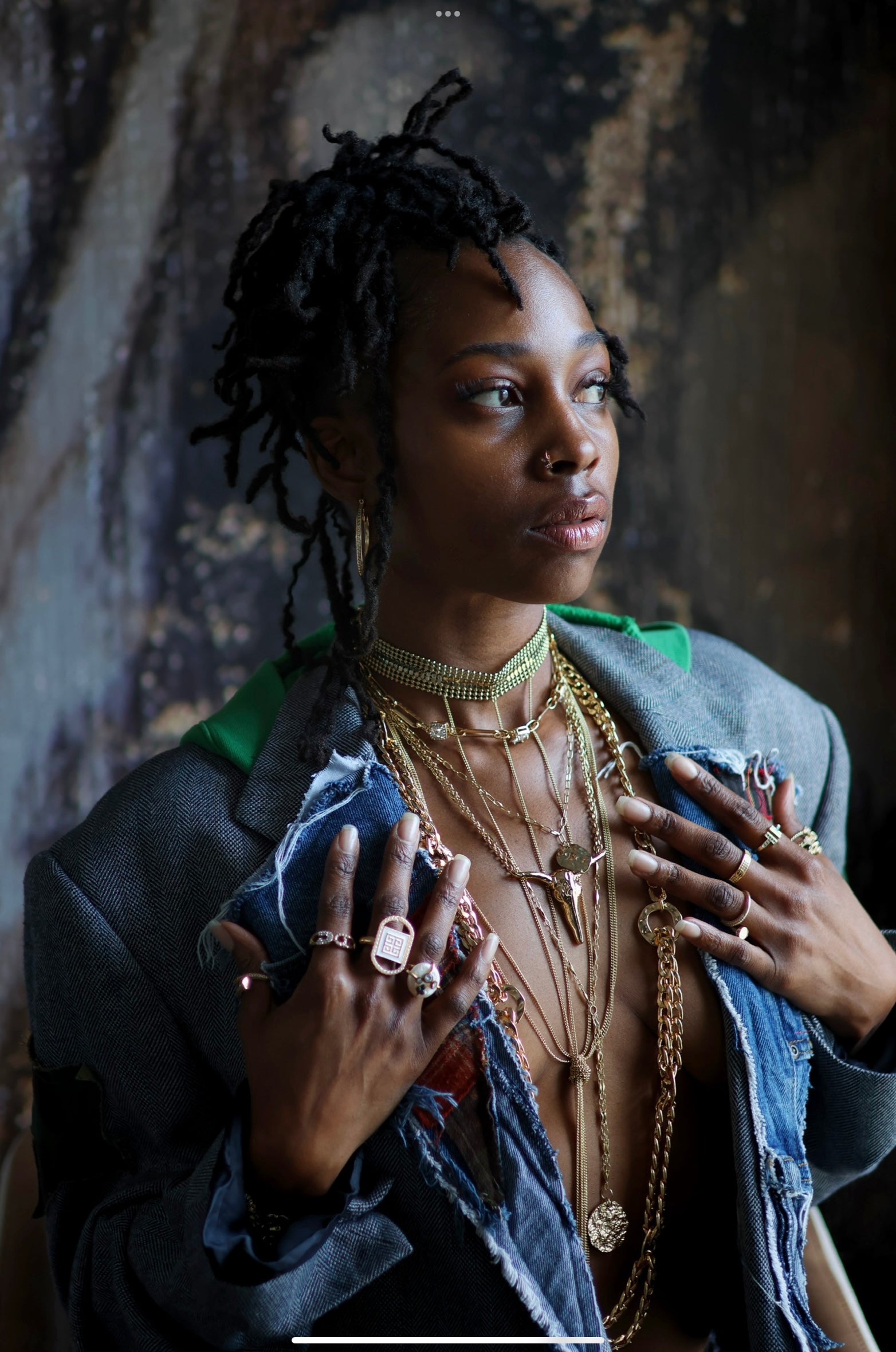 A person showcasing a long horn necklace with multiple chains and separate pieces that flow together into one piece. The setting appears to be indoors with a rustic backdrop.