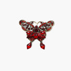 Red butterfly-shaped brooch with gemstones on a white background