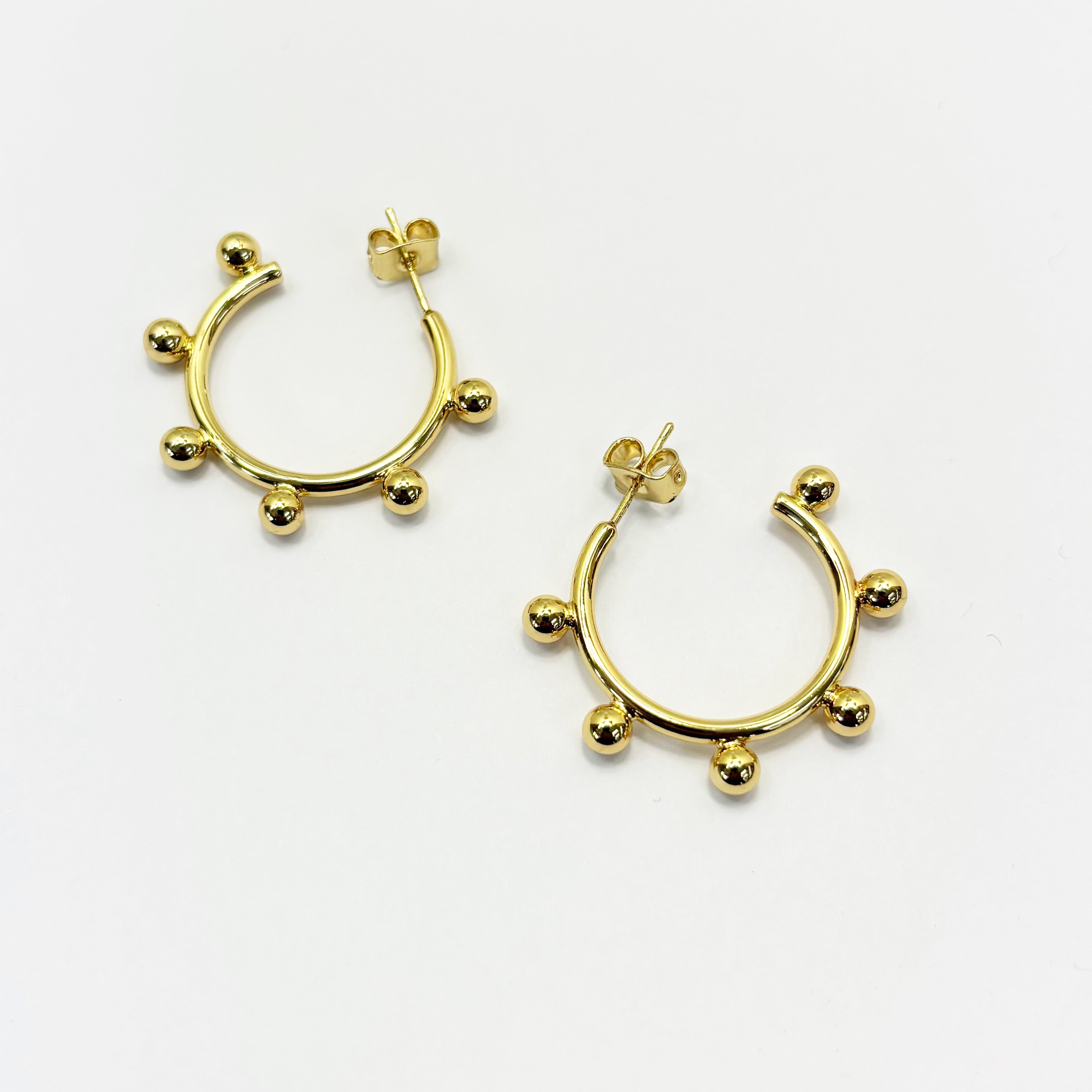 A pair of gold-colored hoop earrings with small silver beads on the hoops.