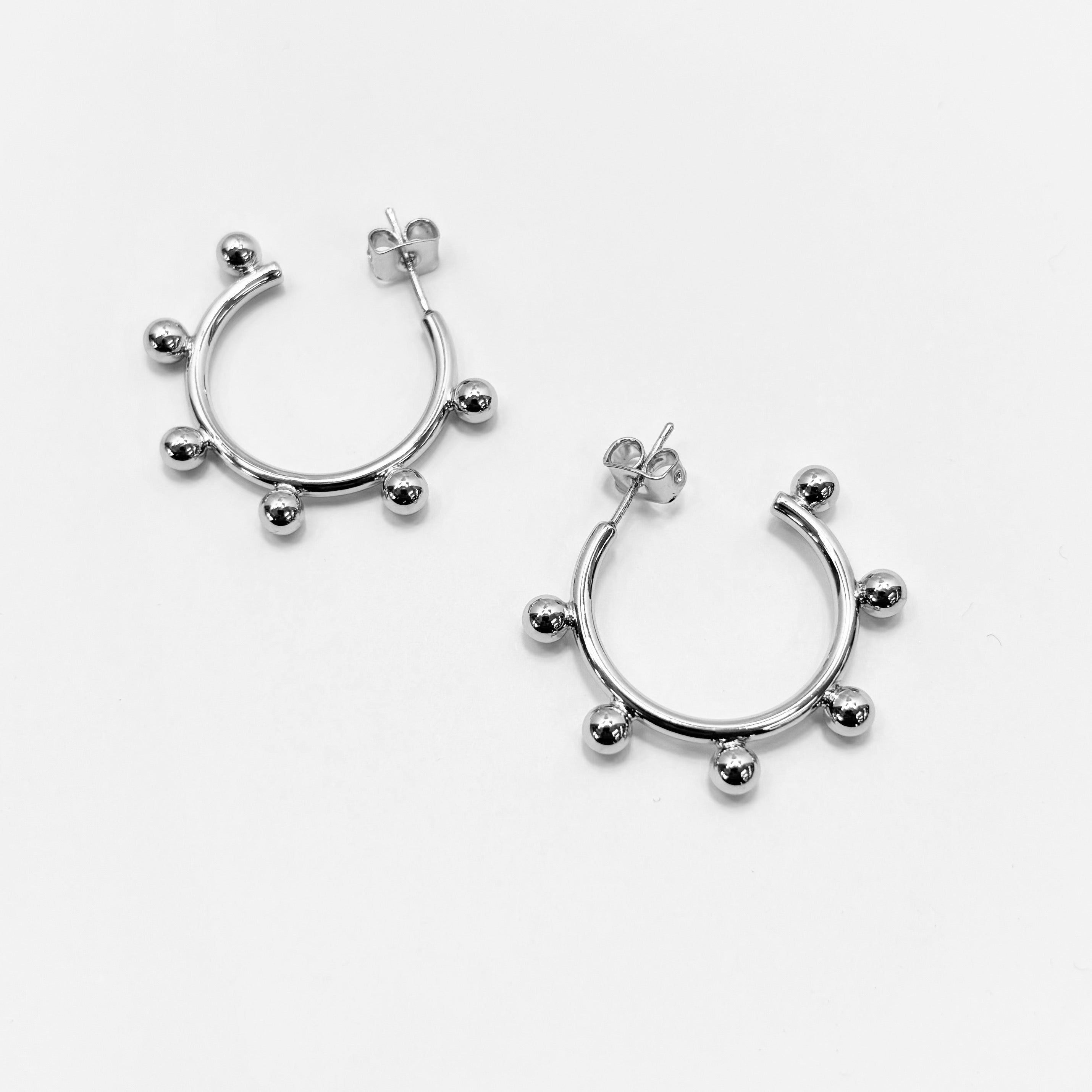 A pair of gold-colored hoop earrings with small silver beads on the hoops.