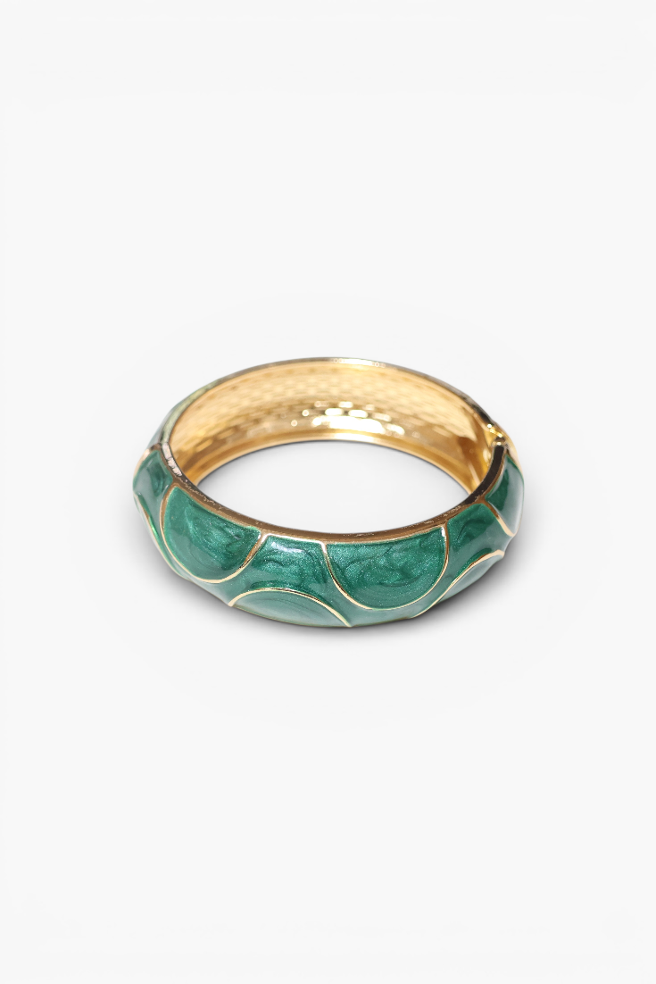 Gold ring with green enamel design on a white background