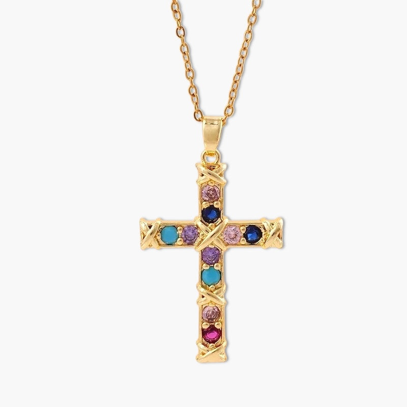 A gold-colored cross necklace with multicolored gemstones on a chain.