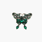 Butterfly-shaped brooch with green gemstones on a white background