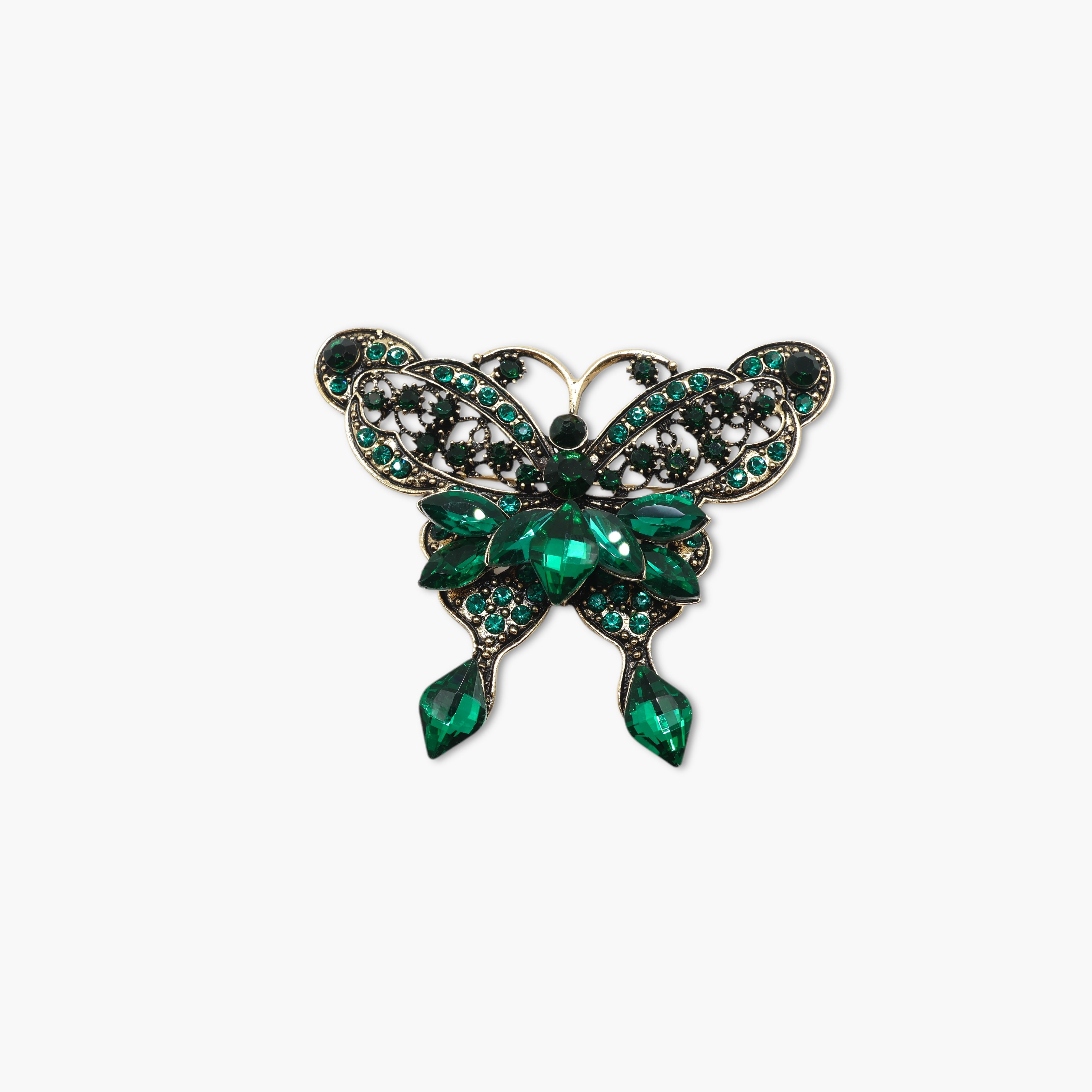 Butterfly-shaped brooch with green gemstones on a white background