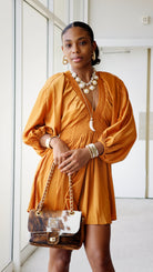 Woman wearing a orange silk dress with a white background