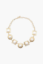 Gold necklace with square and round pendants on a white background