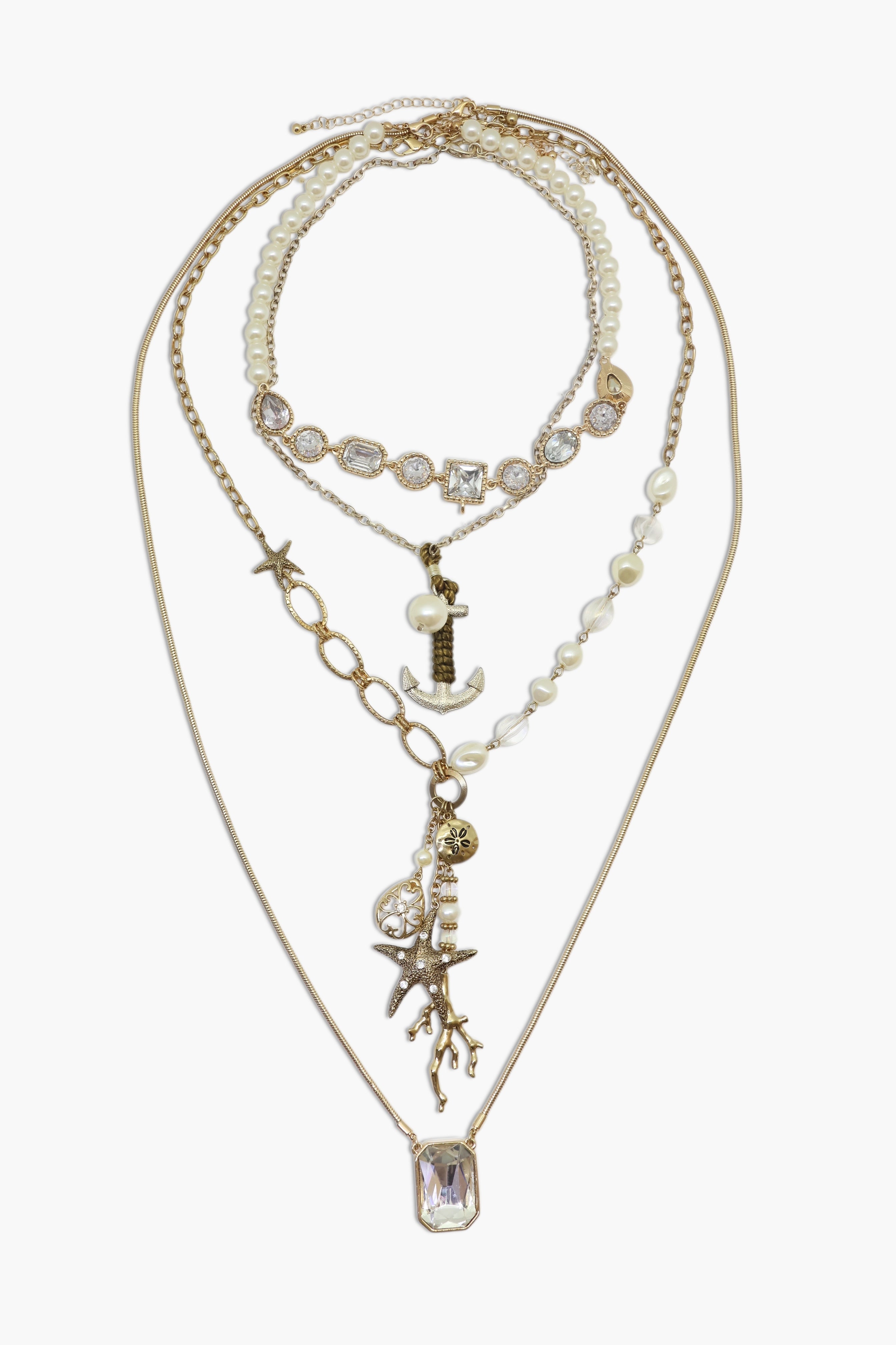 A set of layered necklaces with pearl star fish and anchor charms on a gold-tone chain.