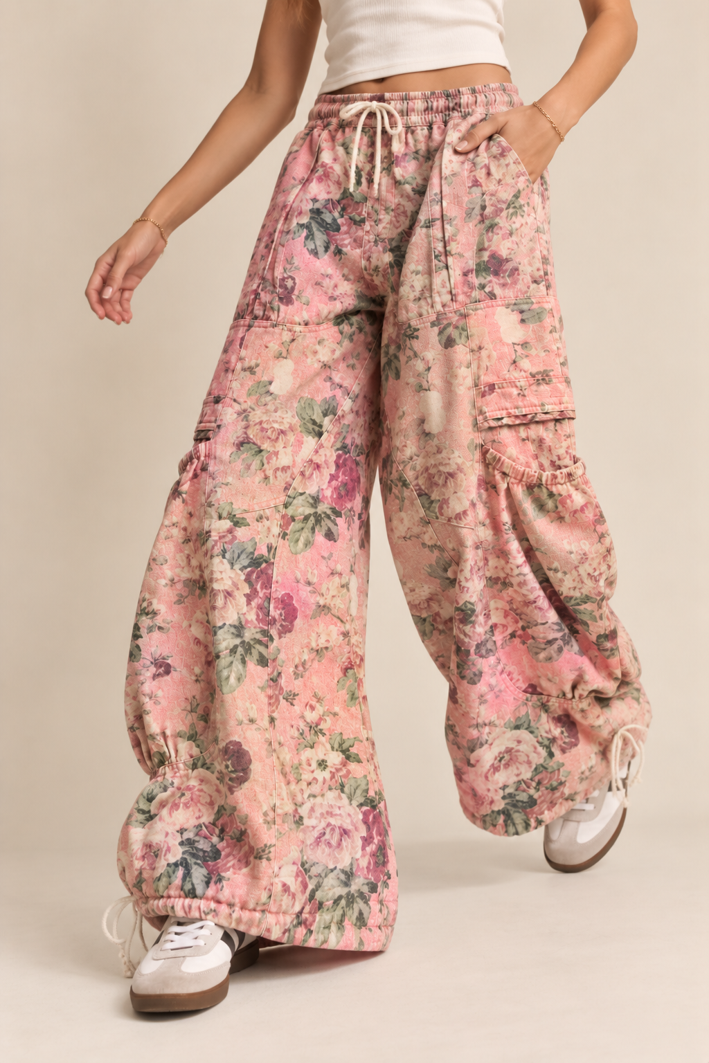 Model wearing wide-leg floral cargo pants with multiple pockets, panel detailing, drawstring waist, and adjustable hems
