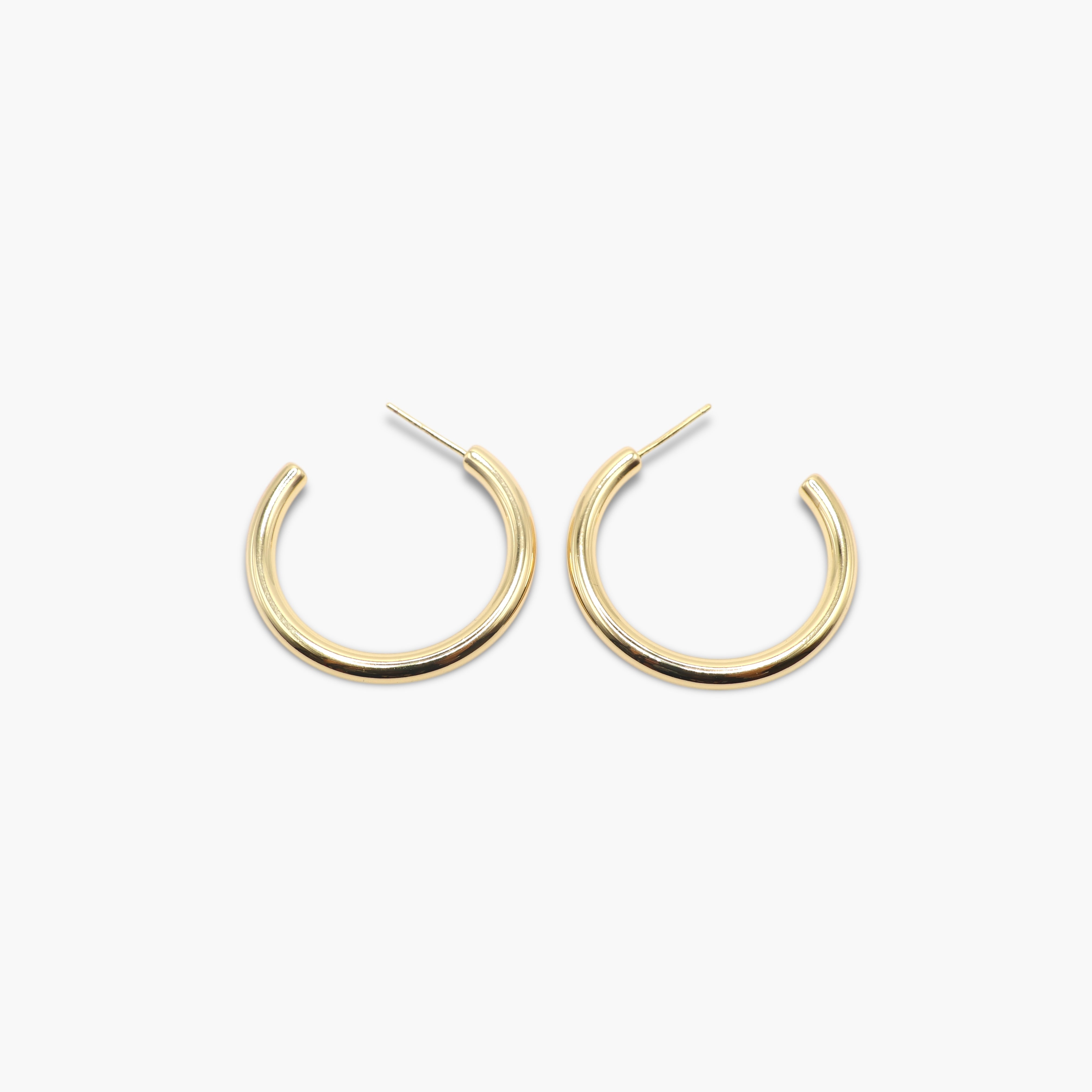 A pair of gold-colored hoop earrings with a textured surface on a white background.
