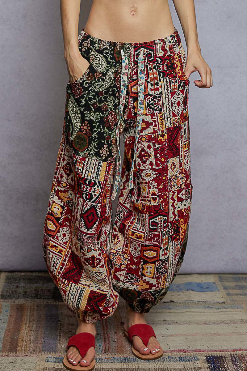 Colorful patterned harem pants worn by a person on a gray background