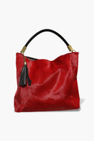 Red handbag with black handle and tassel on a white background