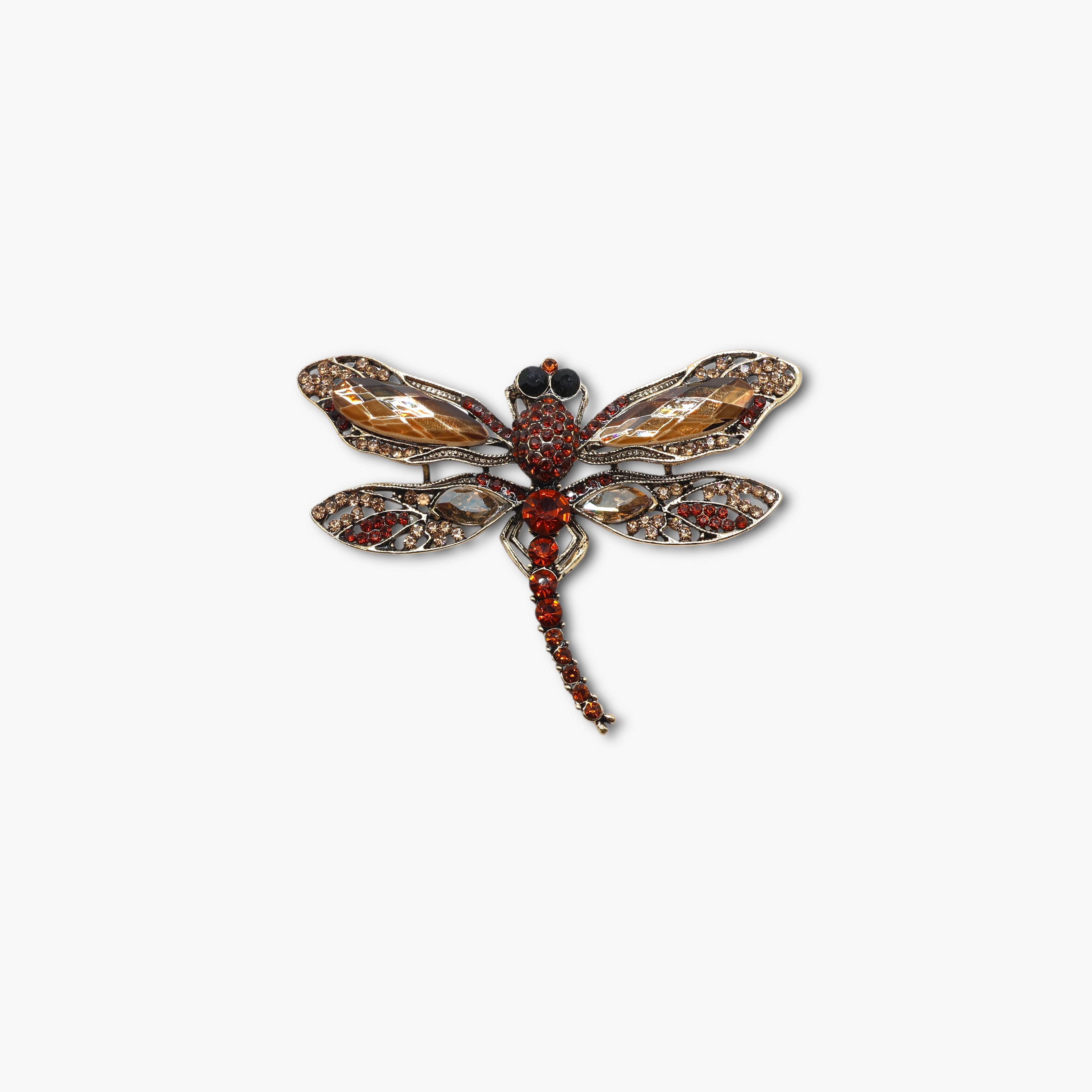 Decorative dragonfly brooch with gemstones on a white background