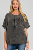 Woman wearing a gray checkered blouse with short sleeves on a gray background