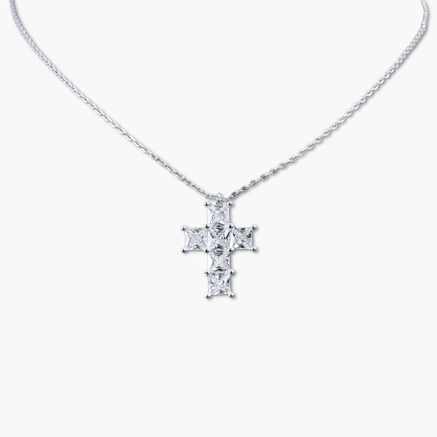 A gold-colored cross necklace with cubic zirconia stones on a white background.
