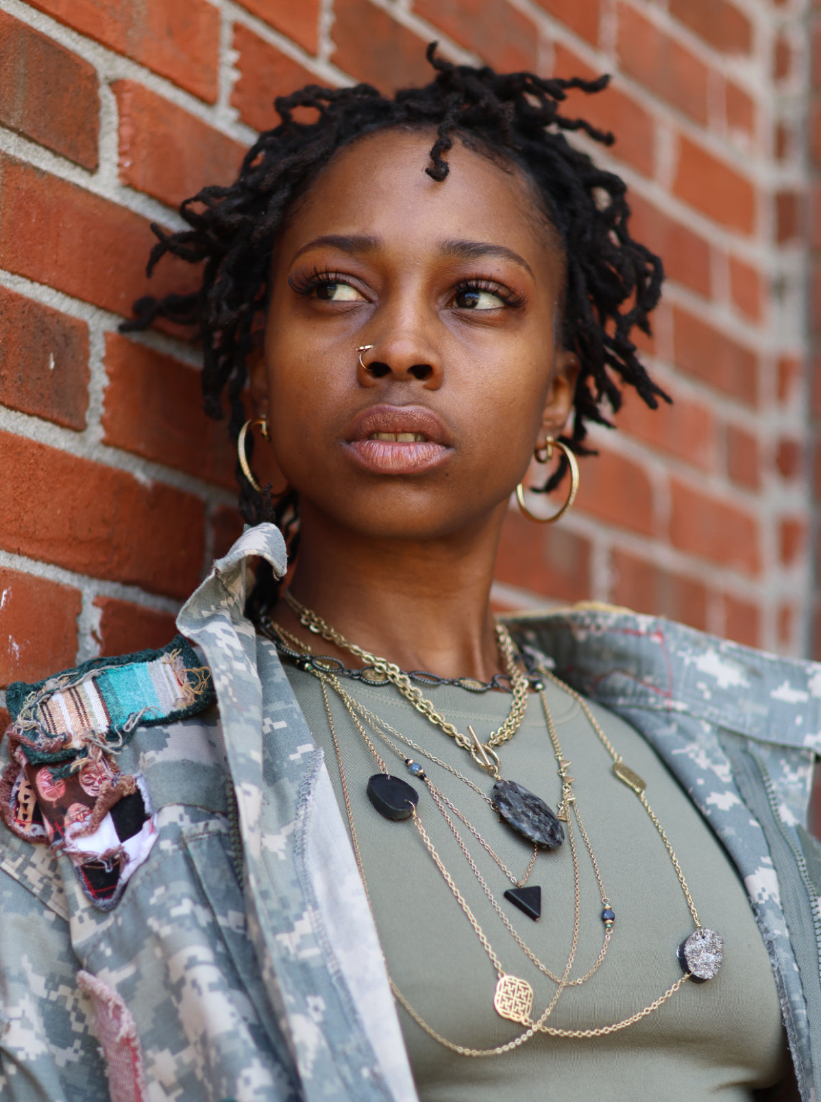 A person wearing multiple necklaces with varying designs and lengths, layered to create a flowing stack effect.
