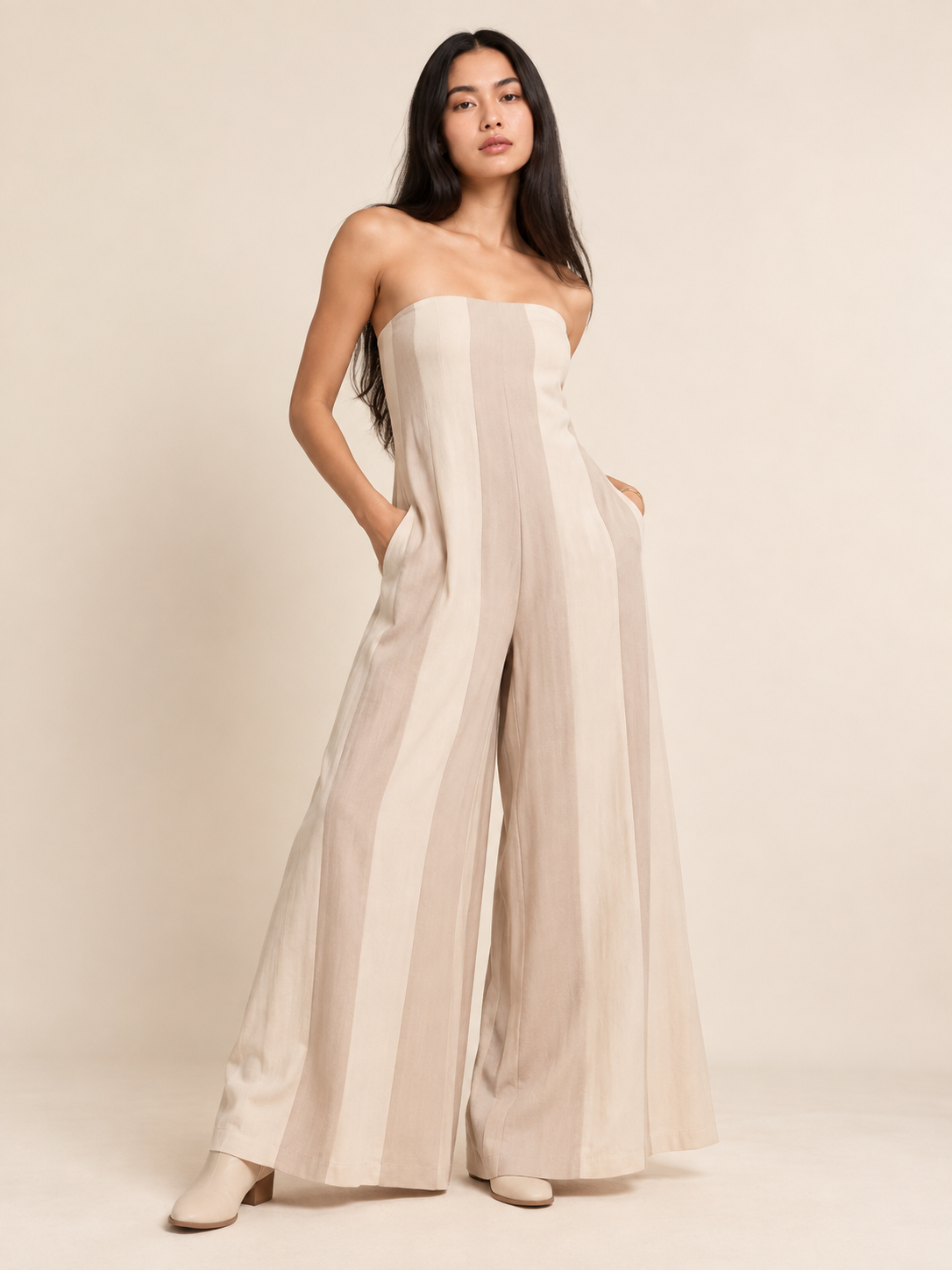 Model wearing a strapless wide-leg jumpsuit with vertical stripe detailing and side pockets