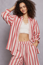 Red and white vertical striped button-down shirt with rolled sleeves, layered over a white lace-trim camisole and paired with matching striped pants, styled on a curly-haired model.