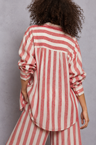Red and white vertical striped button-down shirt with rolled sleeves, layered over a white lace-trim camisole and paired with matching striped pants, styled on a curly-haired model.